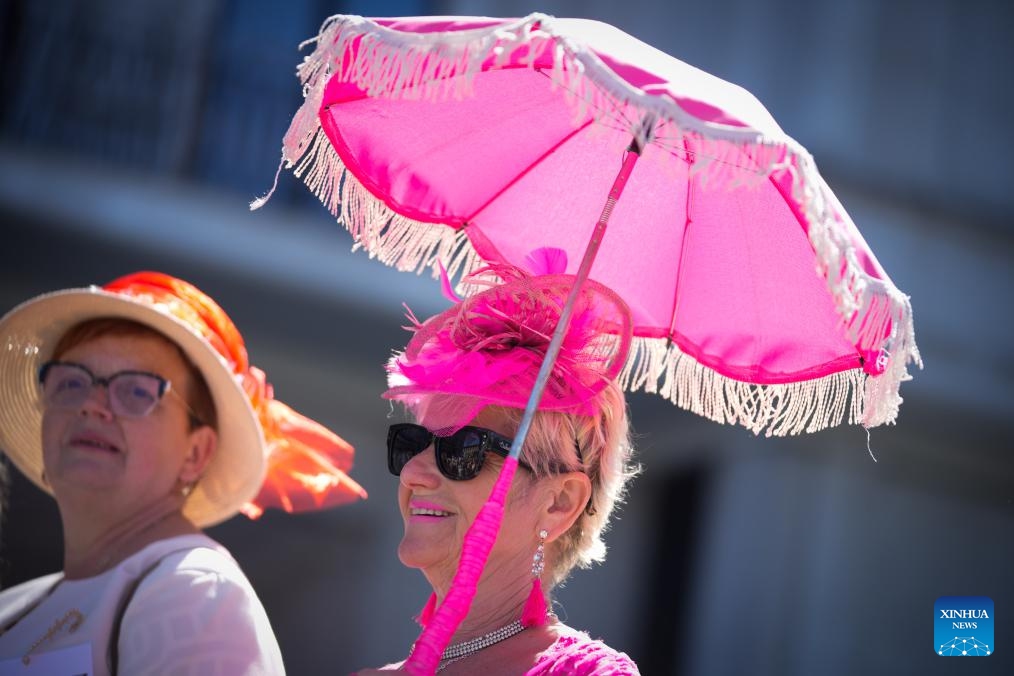 A woman holding a parasol and wearing a pink hat is pictured during the Hat Walk Warsaw event in Warsaw, Poland, May 10, 2026. Participants of the Hat Walk Warsaw event walked along main streets in the city's Old Town to showcase creativity and personal style. (Photo: Xinhua)