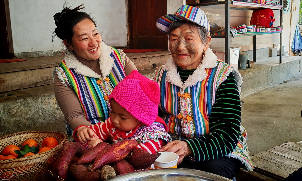 80-year-old face-tattooed woman Li Wenshi (right), her daughter Li Yuhua (left), and her grandson (center) sit in their own courtyard in Dizhengdang village, Dulongjiang, Yunnan Province, on April 16, 2026. Photo: Liang Rui/GT