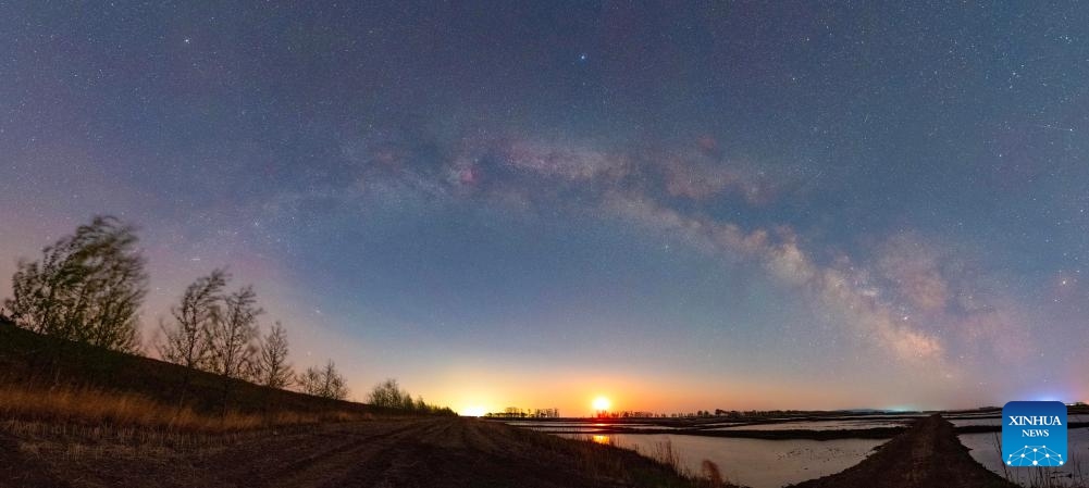 This stitched photo taken on May 11, 2026 shows the Milky Way and the moon above Fujin City, northeast China's Heilongjiang Province. (Photo by Qu Yubao/Xinhua)