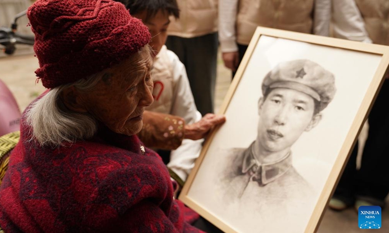Zhong Xindi holds the portrait of his father Zhong Yanzhu, a Red Army martyr, in Ruijin, east China's Jiangxi Province, April 1, 2026. (Xinhua/Zhou Mi)