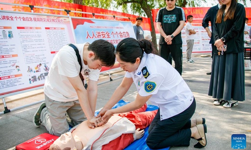 A staff member of a local health committee teaches cardiopulmonary resuscitation (CPR) to residents in Shangqiu City, central China's Henan Province, May 12, 2026. A variety of activities were held across the country marking the National Disaster Prevention and Reduction Day on Tuesday. (Photo by Xu Zeyuan/Xinhua)