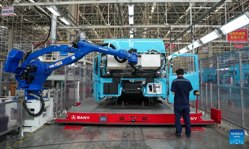 A worker works besides an automated guided vehicle carrying a heavy truck cab at an industrial park of Sany, China's leading heavy equipment manufacturer, in Changsha, central China's Hunan Province, May 12, 2026. Stepping into an intelligent heavy truck industrial park of Sany in Changsha, Hunan Province, one can see a bustling scene on the intelligent production lines.(Xinhua/Xue Yuge)

