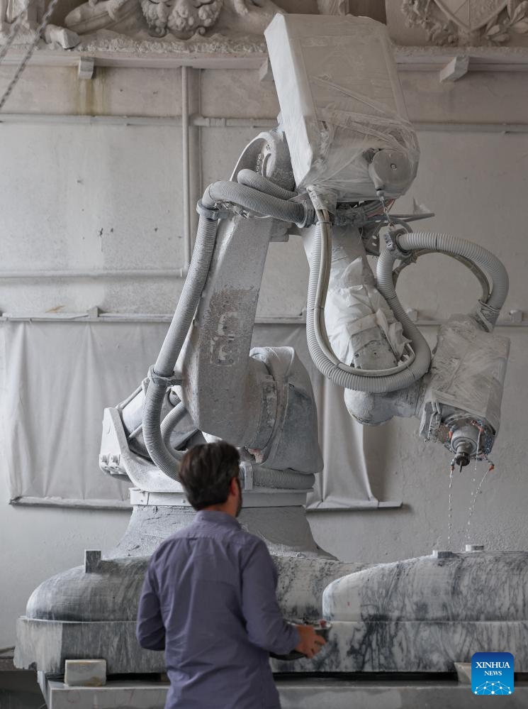 A staff member operates a robot for a marble sculpture at a workshop in Pietrasanta, Italy, May 13, 2026. Pietrasanta has long served as a center for marble sculpture processing in Italy. In recent years, the town's marble workshops have introduced digital technologies to improve the efficiency and quality of their works. (Xinhua/Wang Kaiyan)