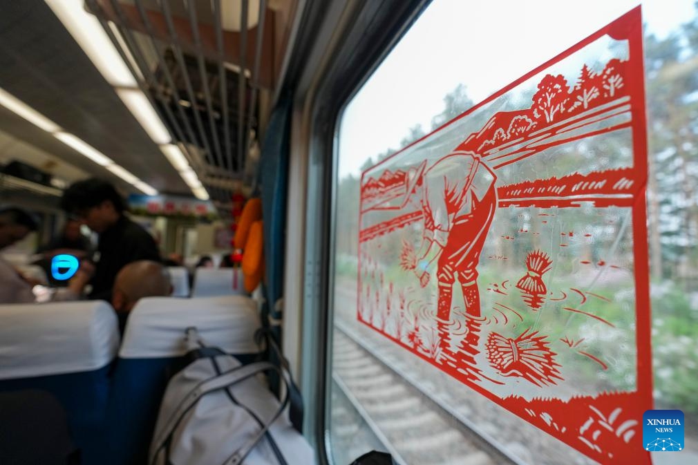 This photo taken on May 13, 2026 shows a paper-cutting depicting a scene of rice transplanting aboard train No. K5153 traveling from Harbin to Fuyuan in northeast China's Heilongjiang Province. The Sanjiang Plain in Heilongjiang Province is a leading grain-producing area in China. Workers are needed there during the transplanting season for rice seedlings.

