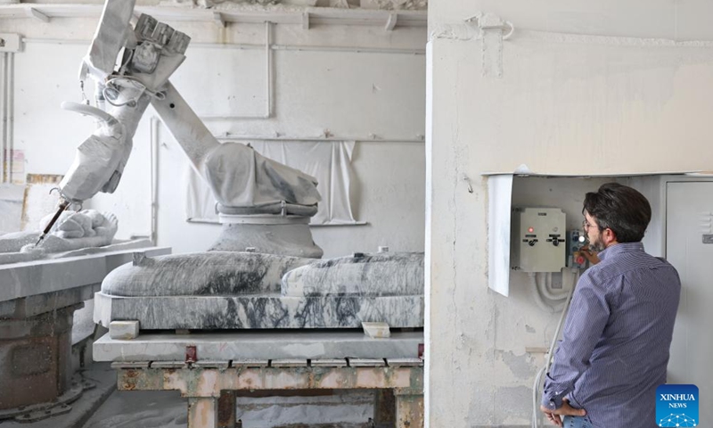 A staff member operates a robot for a marble sculpture at a workshop in Pietrasanta, Italy, May 13, 2026. Pietrasanta has long served as a center for marble sculpture processing in Italy. In recent years, the town's marble workshops have introduced digital technologies to improve the efficiency and quality of their works. (Xinhua/Wang Kaiyan)