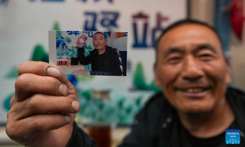 A passenger presents a photo that a conductor has just taken for him aboard train No. K5153 traveling from Harbin to Fuyuan in northeast China's Heilongjiang Province, May 13, 2026. The Sanjiang Plain in Heilongjiang Province is a leading grain-producing area in China. Workers are needed there during the transplanting season for rice seedlings.

