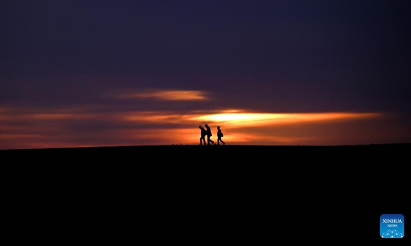 Tourists are pictured at sunrise at the Mingsha Mountain and Crescent Spring Scenic Area in Dunhuang City, northwest China's Gansu Province, May 15, 2026. (Photo by Zhang Xiaoliang/Xinhua)

