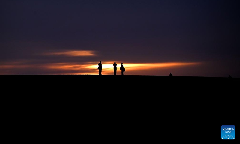 Tourists are pictured at sunrise at the Mingsha Mountain and Crescent Spring Scenic Area in Dunhuang City, northwest China's Gansu Province, May 15, 2026. (Photo by Zhang Xiaoliang/Xinhua)


