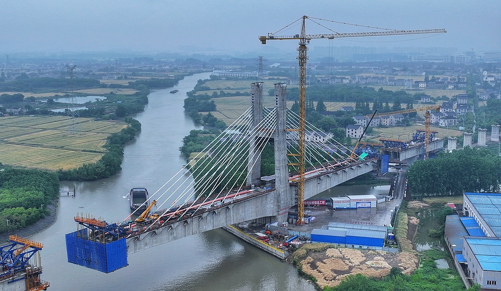 Workers race against the rain to keep construction moving forward at the site of the Nantong-Suzhou-Jiaxing-Ningbo (Tong-Su-Jia-Yong) Railway in Zhangjiagang, East China's Jiangsu Province, on May 20, 2026. The high-speed railway spans about 310 kilometers and is expected to open to traffic in 2027. It will improve regional connectivity and build a