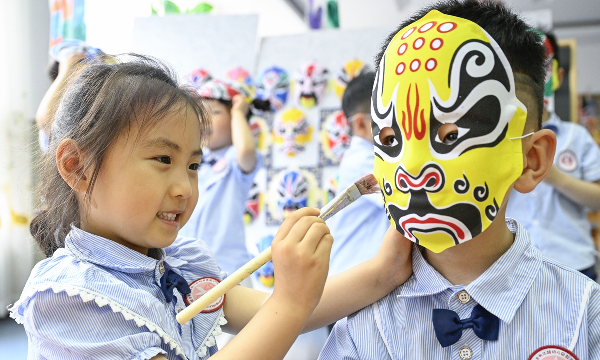 A child from a kindergarten in Hefei, East China's Anhui Province, paints a traditional opera facial mask on her friend on May 14, 2026, as part of an immersive experience in traditional theatrical culture. Photo: VCG