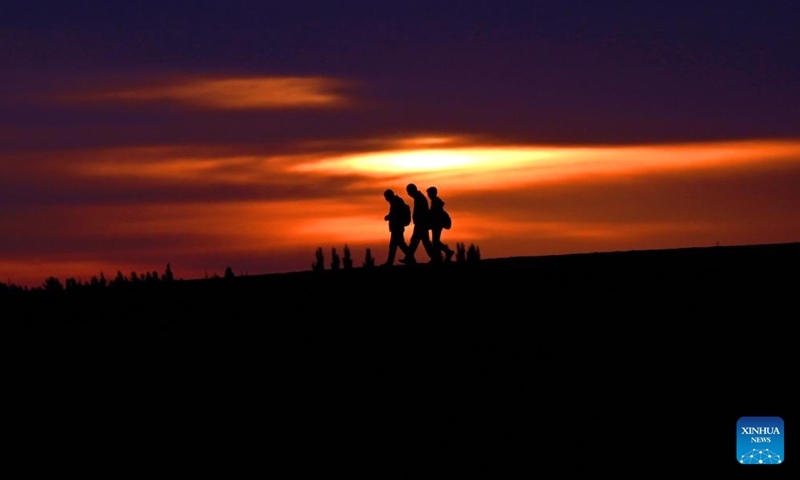 Tourists are pictured at sunrise at the Mingsha Mountain and Crescent Spring Scenic Area in Dunhuang City, northwest China's Gansu Province, May 15, 2026. (Photo by Zhang Xiaoliang/Xinhua)

