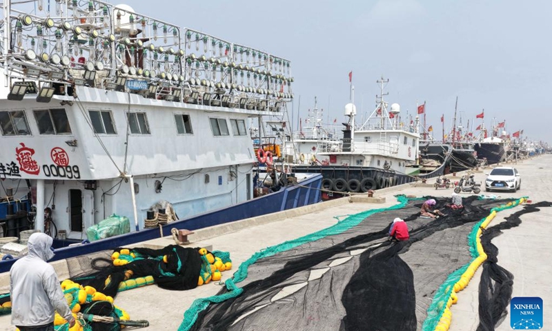 A drone photo taken on May 15, 2026 shows fishers mending fishing nets during the summer fishing moratorium at a fish pier in Heiyanzi Town of Fengnan District, Tangshan, north China's Hebei Province. (Photo: Xinhua)