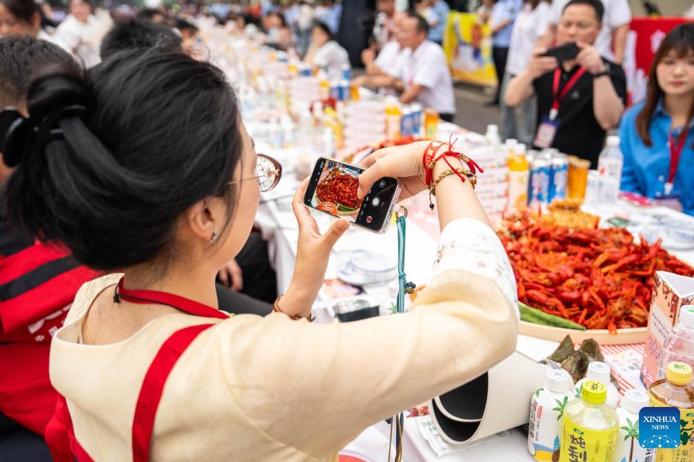 A visitor takes photos of cooked crayfish during a grand crayfish banquet in Nanxian County, Yiyang City of central China's Hunan Province, May 15, 2026. A grand crayfish banquet was held here on Friday. Nanxian County boasts a total arable land area of 630,000 mu (about 42,000 hectares) for shared paddy rice planting and crayfish cultivation, which is now a pillar business for rural revitalization in the county. (Photo: Xinhua)