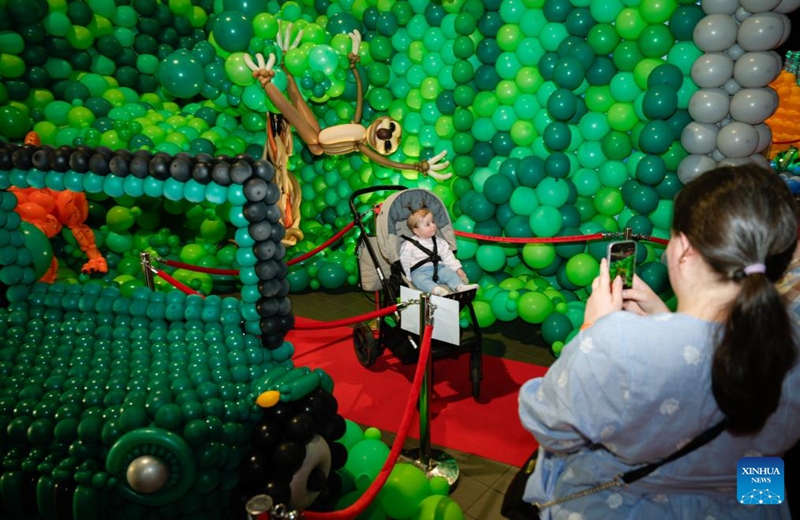 A woman takes photos of a child during the World Balloon Festival in Warsaw, Poland, May 15, 2026. The festival takes place here from May 15 to 17, featuring large themed installations featuring tropical jungles, underwater world, outer space and architectural landmarks created with more than 100,000 biodegradable balloons. (Photo by Jaap Arriens/Xinhua)