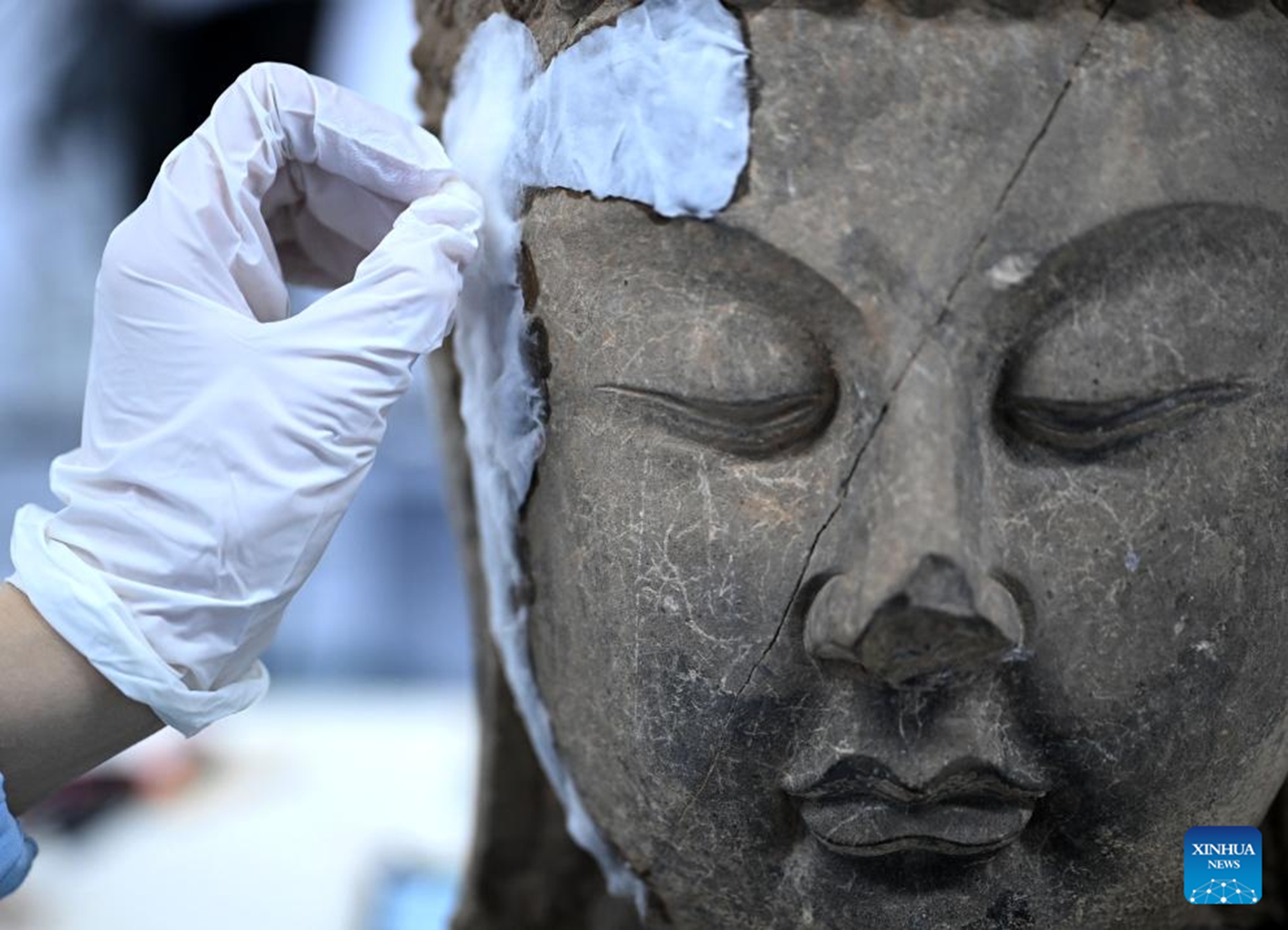 Li Peijun, a member of the conservation, research and monitoring team under Longmen Grottoes Academy, restores a Buddha head at a conservation center of Longmen Grottoes Academy in Luoyang, central China's Henan Province, Dec. 3, 2025. (Xinhua/Li Jianan)