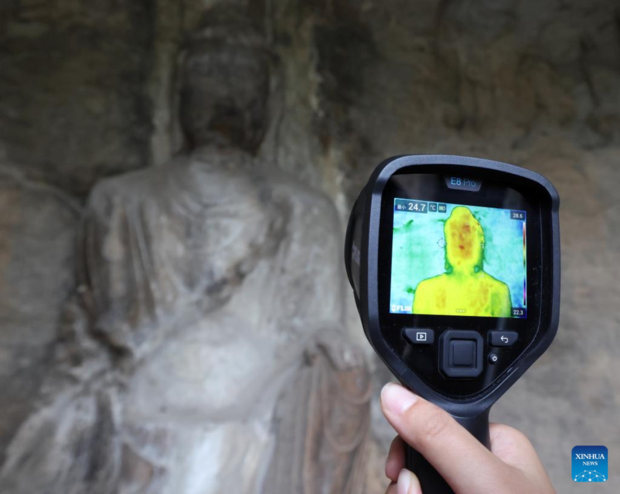 Liu Rui, a member of the conservation, research and monitoring team under Longmen Grottoes Academy, checks for water leakage points with an infrared thermal imaging camera at a cave of Longmen Grottoes in Luoyang, central China's Henan Province, May 12, 2026. (Xinhua/Li Jianan)