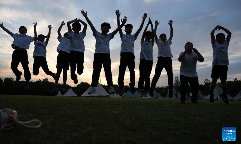Sixth-grade students pose for group photos during a graduation camping night event at a school in Wuchang District of Wuhan, central China's Hubei Province, May 15, 2026. The school held the event here on Friday for more than 300 sixth-grade students who are about to graduate. (Xinhua/Xiao Yijiu)