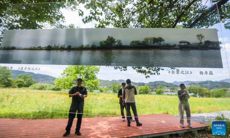 People view an open air art exhibition in Zhijiang Village of Xiaya Town, Jiande City of east China's Zhejiang Province, May 16, 2026. A photography + oil painting dual art exhibition was unveiled in Zhijiang Village of Xiaya Town on Saturday. Breaking the conventional boundaries of traditional art galleries, the exhibition is set amid fields, forests, and village paths. A total of 90 photography and oil painting works showcased the local rural customs and landscapes, with the majority of the artists being local villagers. Photo: Xinhua