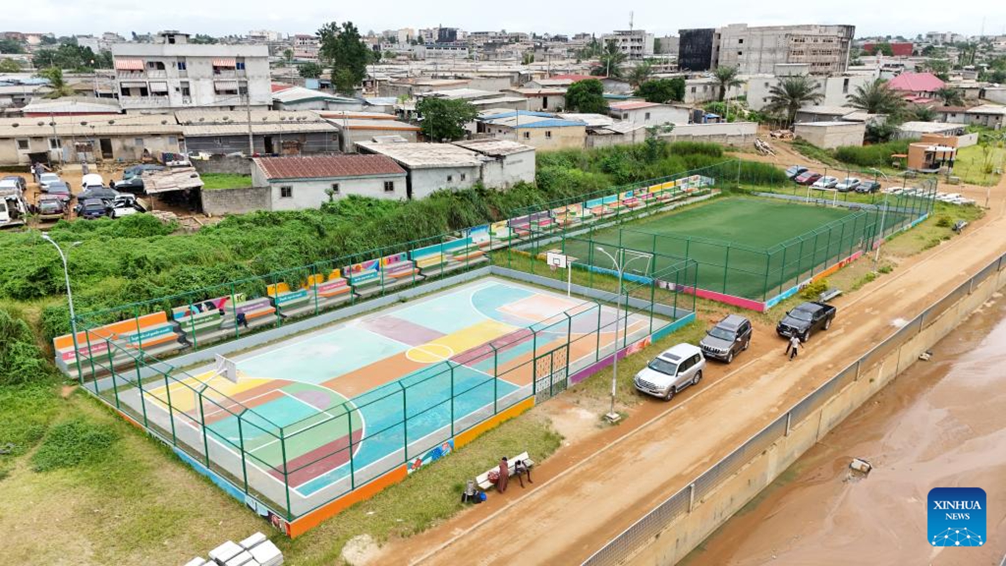 An aerial drone photo taken on April 22, 2026 shows a newly-built drainage channel, as well as football and basketball fields along it, in the Abobo commune in northern Abidjan, Cote d'Ivoire. TO GO WITH Feature: Chinese-built drainage project transforms Cote d'Ivoire's flood-prone commune (Power Construction Corporation of China/Handout via Xinhua)

