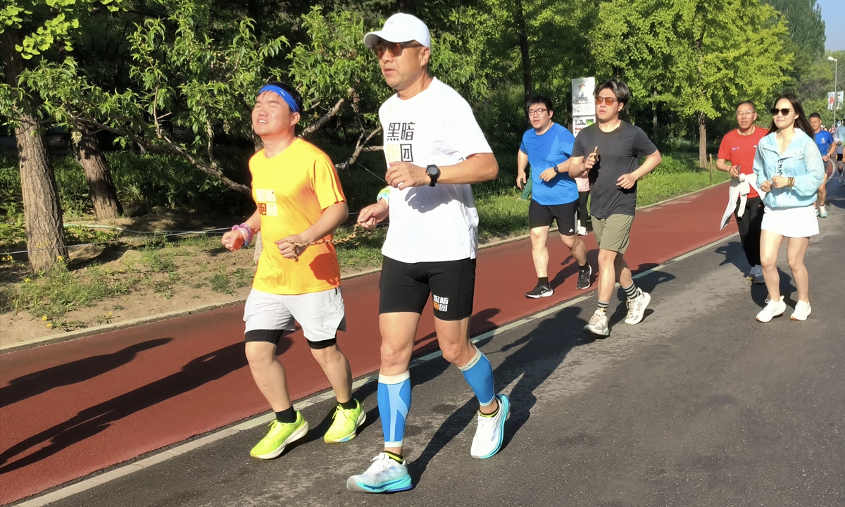 A visually impaired runner (left) is training at the Olympic Forest Park in Beijing with the assistance of a guide runner in May 2026. Photo: Courtesy of organizers