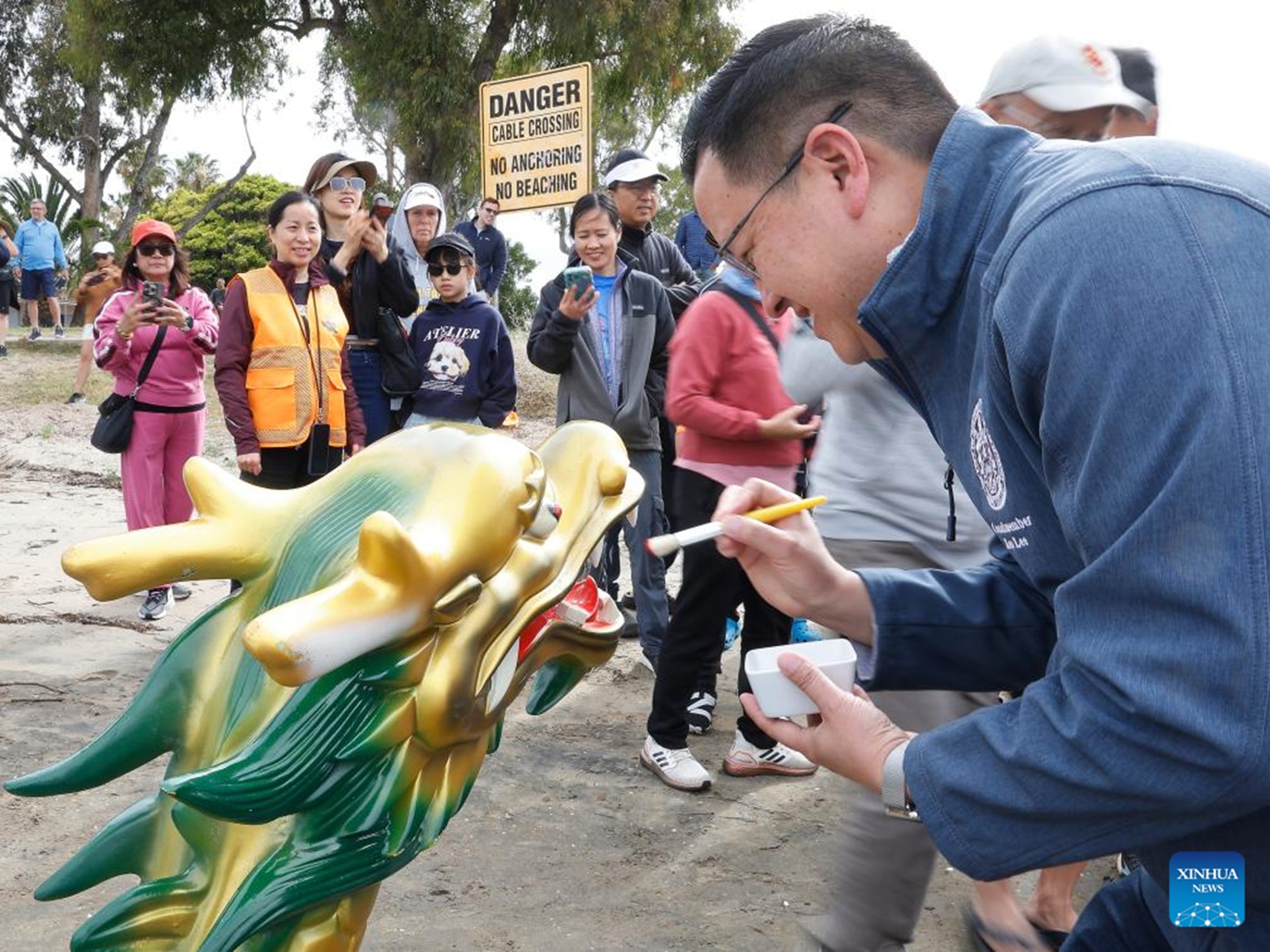 Kent Lee, president pro tempore of the San Diego City Council, dots the eyes of a dragon boat before the start of races during the annual San Diego Dragon Boat Festival at Mission Bay in San Diego, California, the United States, on May 16, 2026. (Photo by Qiu Chen/Xinhua)

