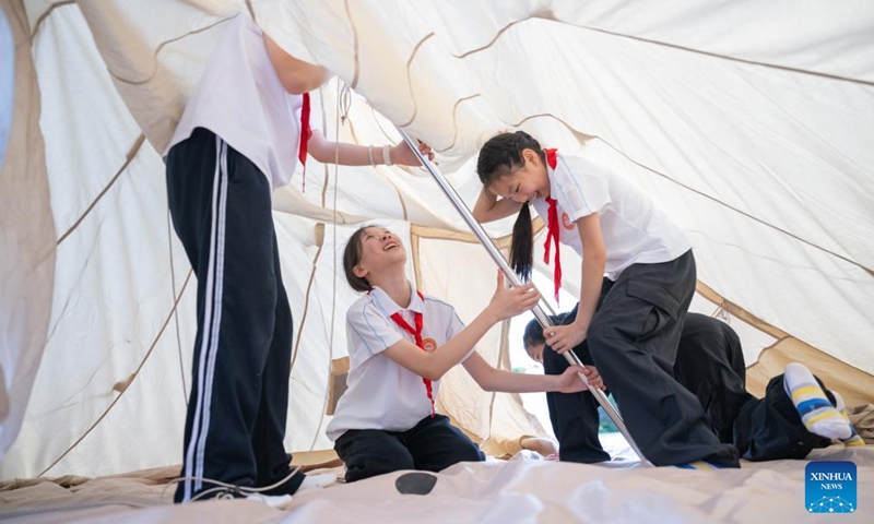 Sixth-grade students put up a tent during a graduation camping night event at a school in Wuchang District of Wuhan, central China's Hubei Province, May 15, 2026. The school held the event here on Friday for more than 300 sixth-grade students who are about to graduate. (Xinhua/Xiao Yijiu)