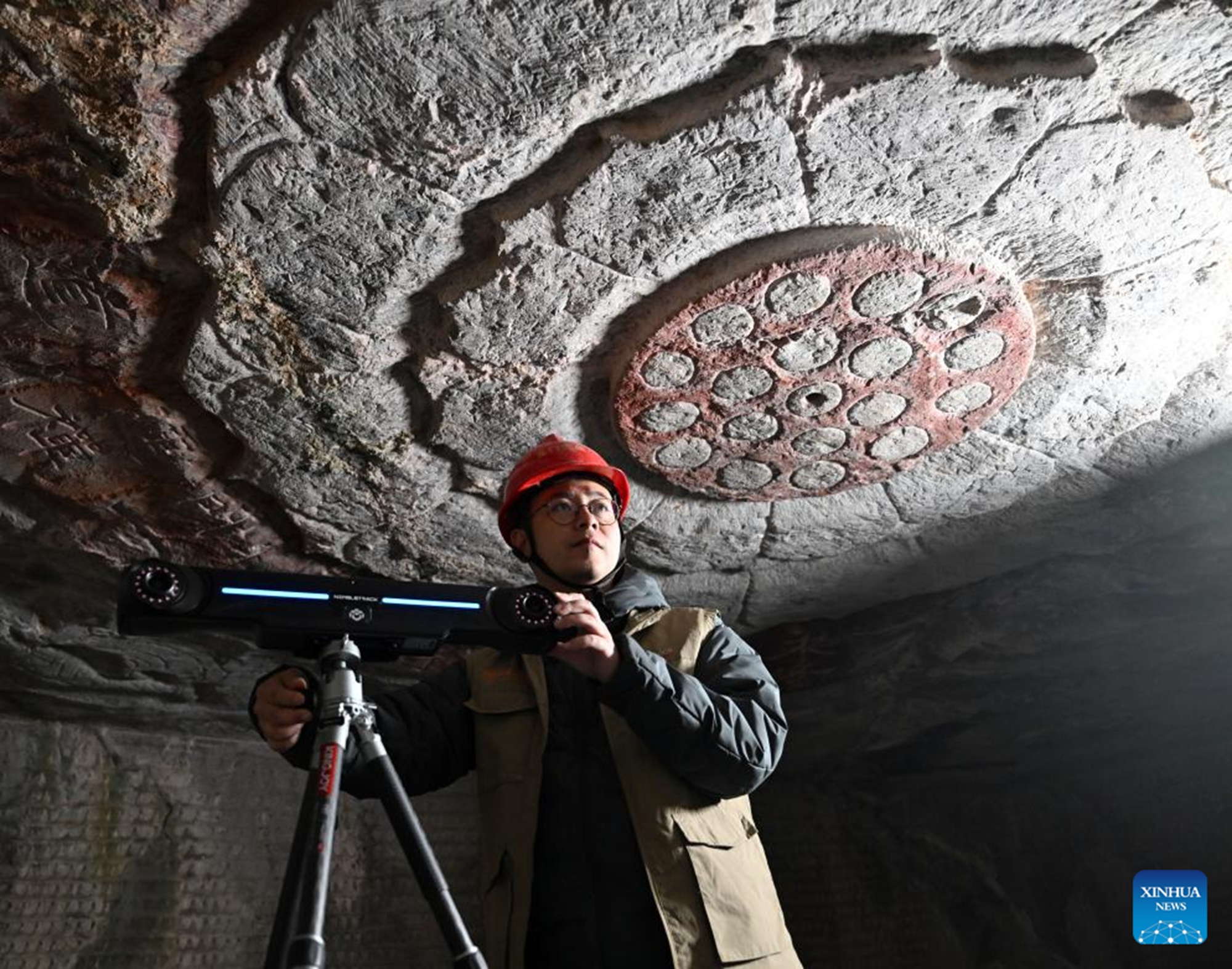Zhang Guofeng, a member of the conservation, research and monitoring team under Longmen Grottoes Academy, adjusts scanning devices at a cave of Longmen Grottoes in Luoyang, central China's Henan Province, Dec. 3, 2025. (Xinhua/Li Jianan)