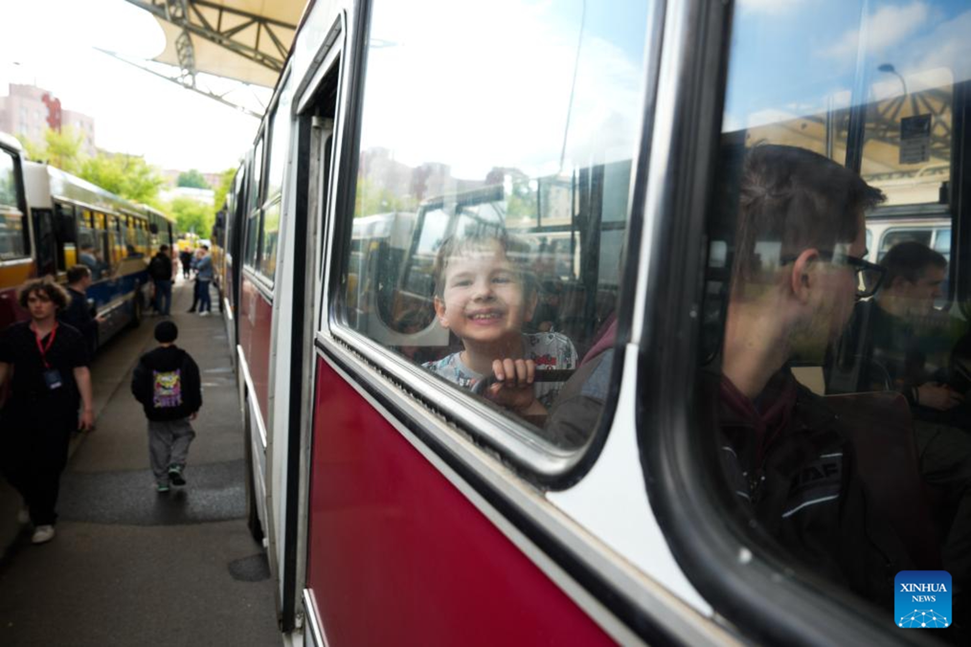 A child smiles while riding a vintage bus in Warsaw, Poland, on May 16, 2026. Vintage bus-riding event in Warsaw attracts residents and tourists to experience the history of public transportation. (Photo by Jaap Arriens/Xinhua)