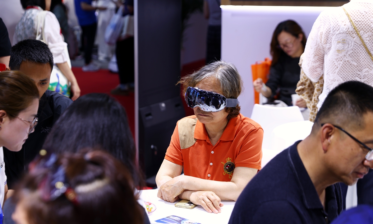 An aged visitor tests an eye care device at the 12th China International Senior Services Expo, which kicked off in Beijing on May 18, 2026. The two-day event features 10 themed exhibition areas, including 