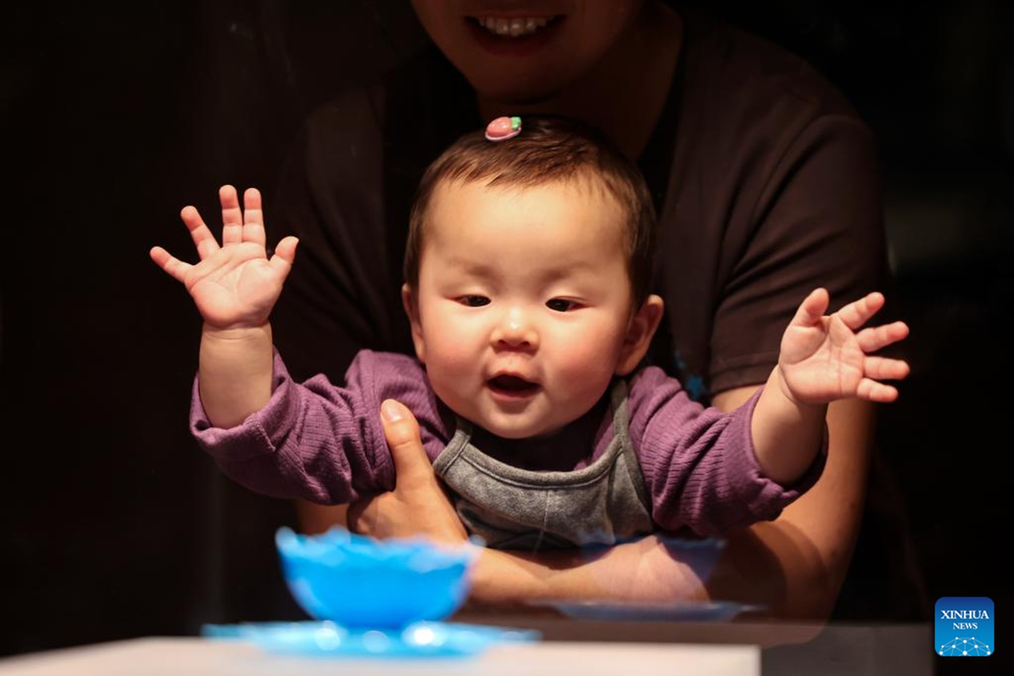 A visitor with a baby looks at a cultural relic on display at Gansu Provincial Museum in Lanzhou, northeast China's Gansu Province, May 16, 2026. Museums across China receive large numbers of visitors with the upcoming International Museum Day, which will fall on May 18. (Photo by Hou Chonghui/Xinhua)