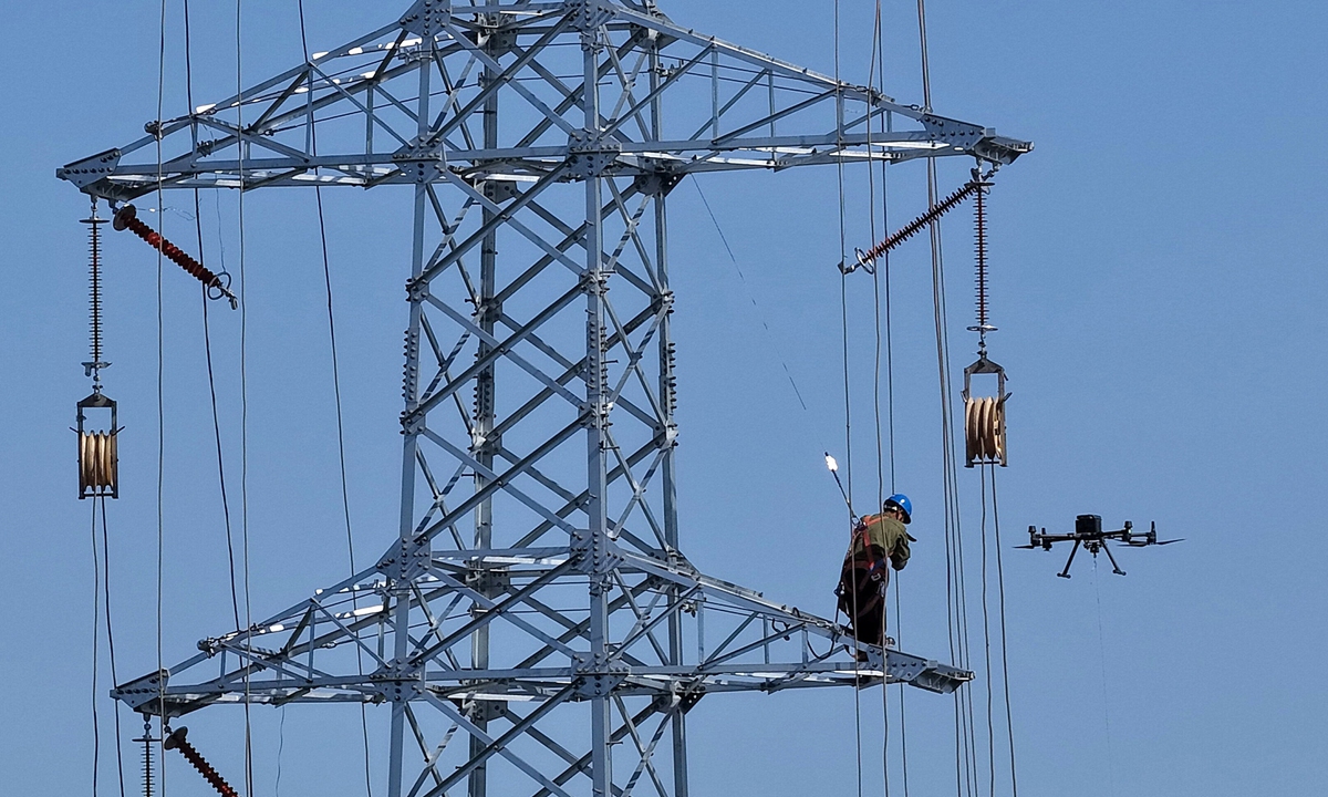 Construction workers from the Nantong branch of State Grid use a drone to carry a guide rope for intelligent transmission line construction at a site in Hai'an city, East China's Jiangsu Province on May 18, 2026. This modern technological approach replaces traditional manual operations, effectively improving the safety and efficiency of power grid construction. Photo: VCG