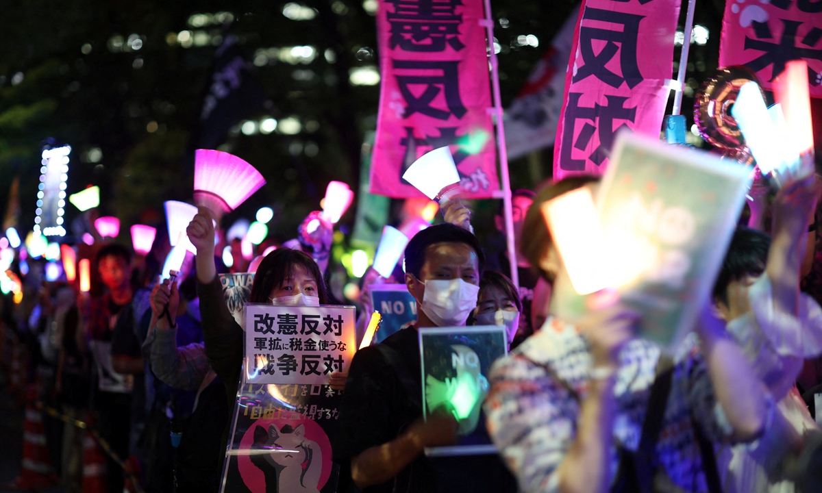 Protesters hold placards and lights during a rally against Japanese Prime Minister Sanae Takaichi's constitutional revision and military expansion policies, in front of the parliament building in Tokyo, Japan on May 19, 2026. Photo: IC