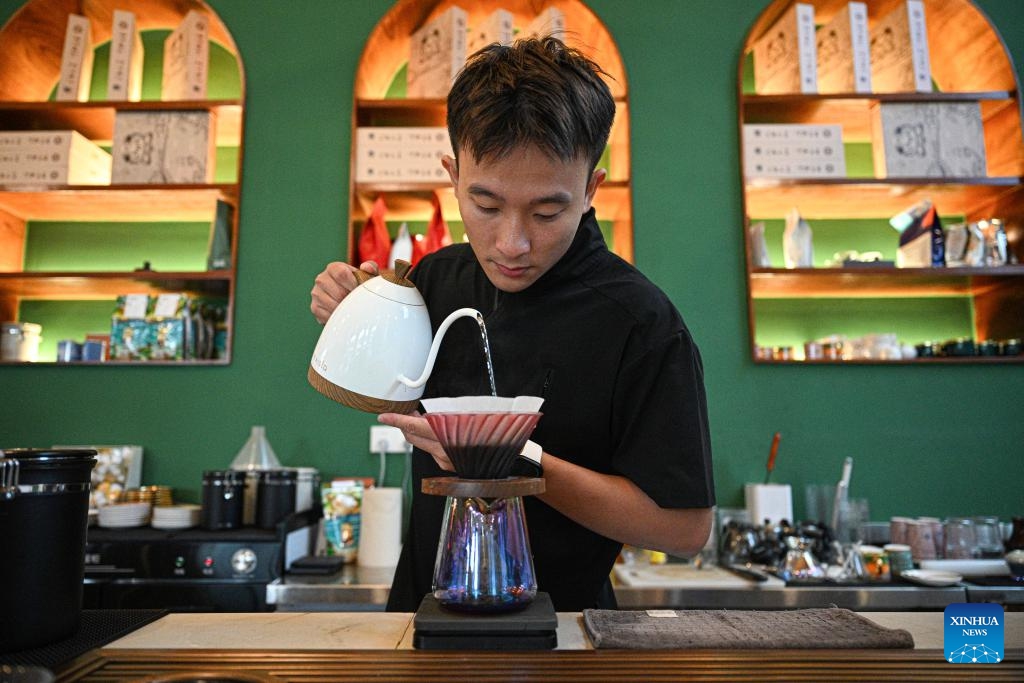 A staff member brews coffee at a cafe in Wenchang, south China's Hainan Province, May 15, 2026. Wenchang in south China's Hainan is a renowned hometown of overseas Chinese, where cultures brought back by overseas Chinese from Southeast Asia have merged with the indigenous ones to form some very interesting customs in diet and entertainment.The influence of overseas Chinese is evident throughout Wenchang. (Photo: Xinhua)