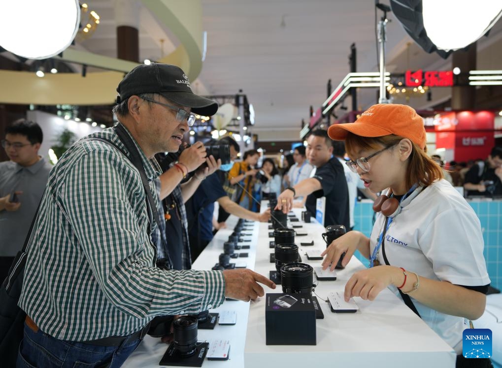 Visitors learn about lenses at the exhibition area of Viltrox at the 27th China International Photograph & Electrical Imaging Machinery and Technology Fair (China P&E) at the Beijing Exhibition Center in Beijing, capital of China, May 18, 2026. The 27th China International Photograph & Electrical Imaging Machinery and Technology Fair (China P&E) concluded here on Monday. With an exhibition area of more than 20,000 square meters, the event gathered more than 120 exhibitors, covering a full range of imaging gear including camera, lens, lighting equipment, storage device and others. (Photo: Xinhua)