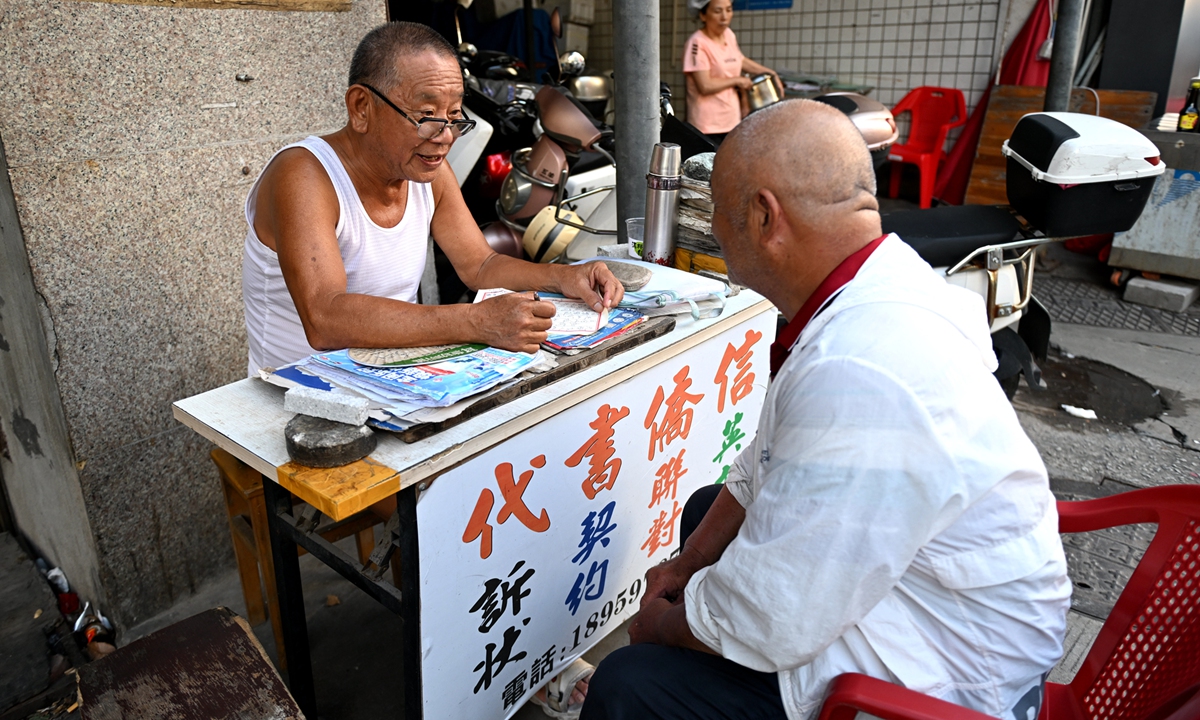 Jiang Mingdian (left) talks with a customer at his roadside stall in Quanzhou, East China's Fujian Province, on July 13, 2025. Photo: VCG