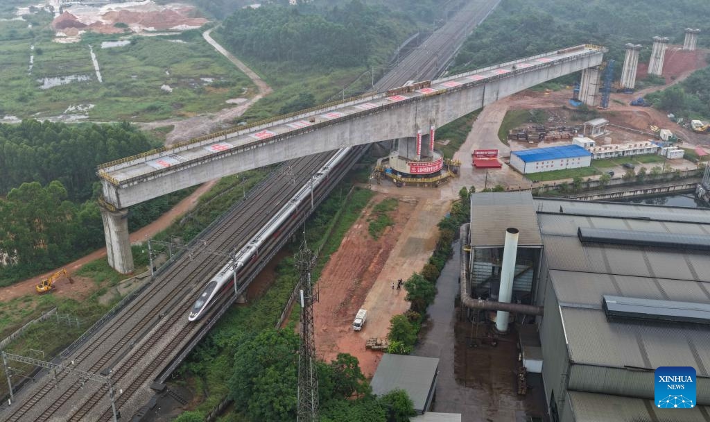 An aerial drone photo taken on May 19, 2026 shows a high-speed train running under a continuous beam, already rotated to its desired position, of the Xijiang River Grand Bridge on the Zhuhai-Zhaoqing high-speed railway in Zhaoqing, south China's Guangdong Province. A rotating girder of the Xijiang River Grand Bridge completed its rotation on Tuesday, crossing two existing high-speed railways. The 8,324-meter bridge is a key project of the Zhuhai-Zhaoqing high-speed railway under construction. The railway is expected to improve transport links in the Guangdong-Hong Kong-Macao Greater Bay Area. (Photo: Xinhua)