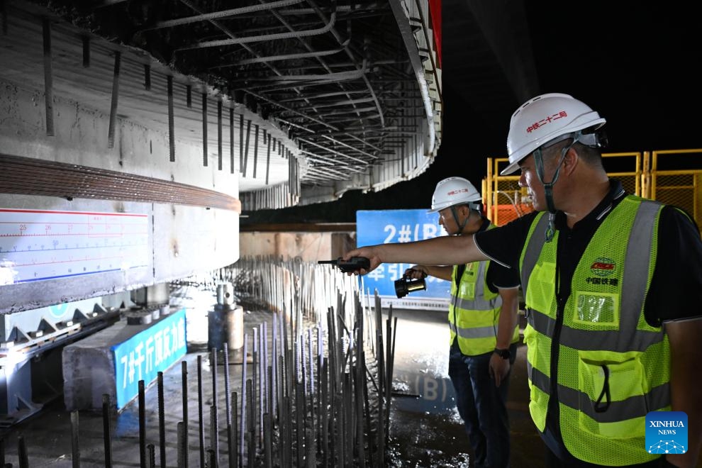 Staff members check a continuous beam of the Xijiang River Grand Bridge ahead of its rotation process in Zhaoqing, south China's Guangdong Province, on May 18, 2026. A rotating girder of the Xijiang River Grand Bridge completed its rotation on Tuesday, crossing two existing high-speed railways. The 8,324-meter bridge is a key project of the Zhuhai-Zhaoqing high-speed railway under construction. The railway is expected to improve transport links in the Guangdong-Hong Kong-Macao Greater Bay Area. (Photo: Xinhua)