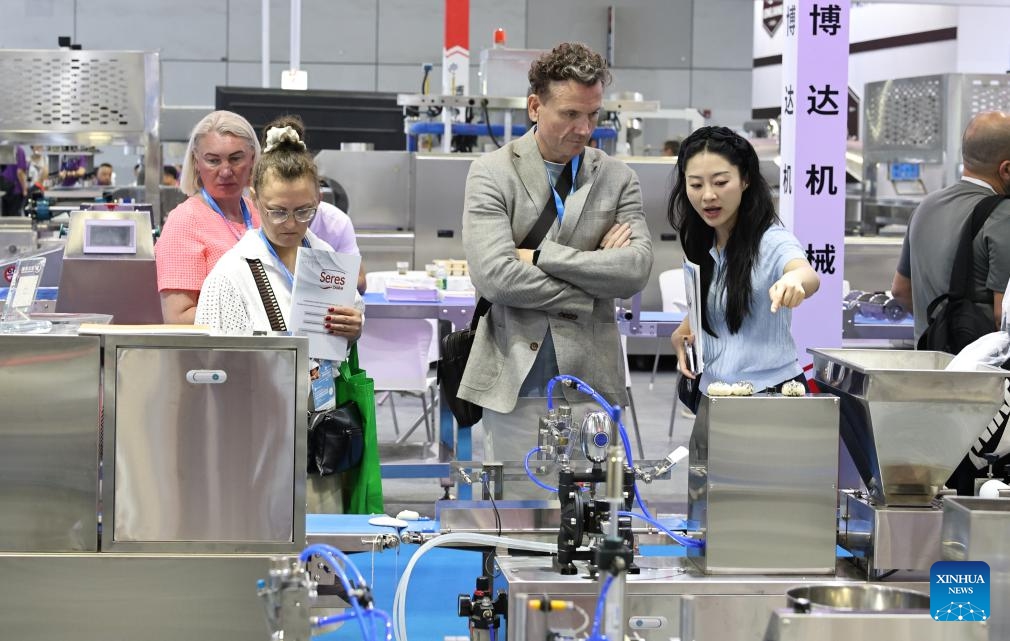 Foreign merchants view a set of food equipment during Bakery China 2026 at National Exhibition and Convention Center in Shanghai, east China, May 20, 2026. Bakery China 2026 opened here on Wednesday. Covering 330,000 square meters show space, the exhibition attracts over 2,200 exhibitors from more than 70 countries and regions, showcasing the whole industry chain products of the baking industry, from raw materials, technical equipment to integrated solutions. (Photo: Xinhua)