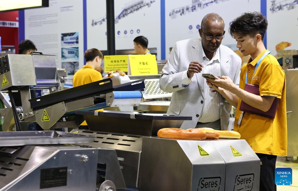 A staff member (R) introduces products to a foreign merchant during Bakery China 2026 at National Exhibition and Convention Center in Shanghai, east China, May 20, 2026. Bakery China 2026 opened here on Wednesday. Covering 330,000 square meters show space, the exhibition attracts over 2,200 exhibitors from more than 70 countries and regions, showcasing the whole industry chain products of the baking industry, from raw materials, technical equipment to integrated solutions. (Photo: Xinhua)