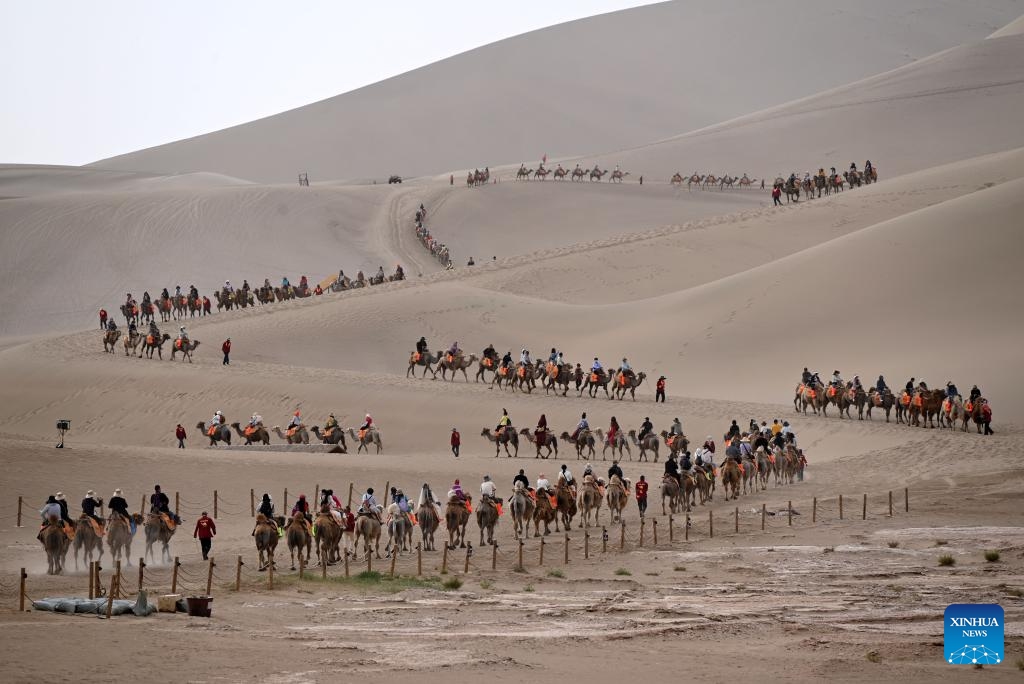 Tourists ride camels at the Mingsha Mountain and Crescent Spring Scenic Area in Dunhuang, northwest China's Gansu Province, May 19, 2026. This Tuesday marks the 16th China Tourism Day. (Photo: Xinhua)