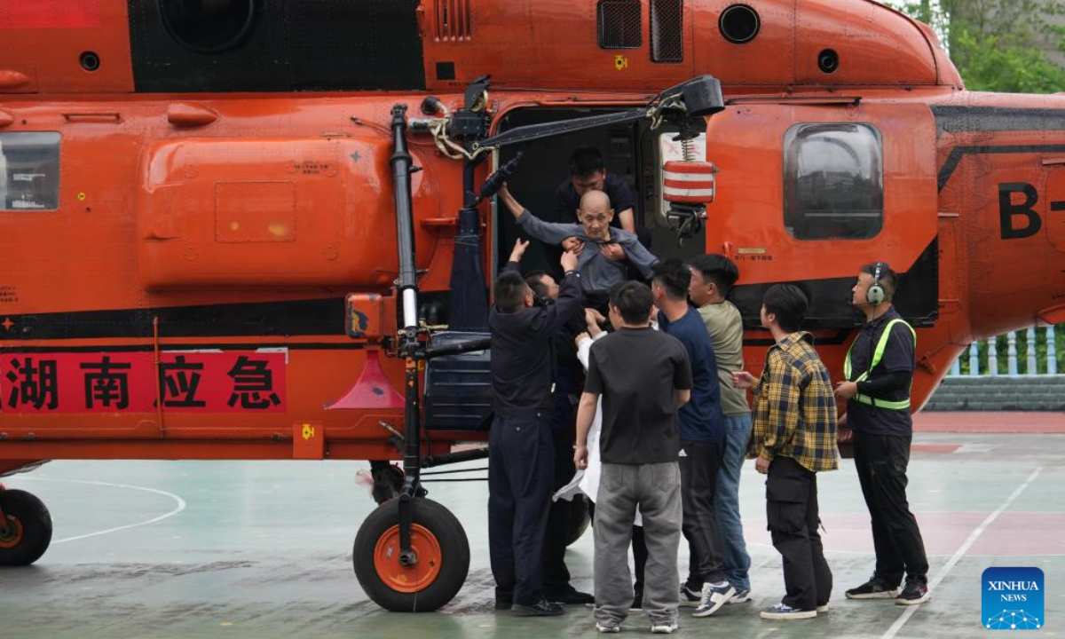 Disaster-affected villagers get off a helicopter with the help of staff members in Shimen County, Changde City of central China's Hunan Province, May 21, 2026. Recently, some areas in Hunan have been hit by severe flooding, resulting in heavy casualties and property losses. Continuous heavy rainfall has lashed the province's Shimen County, leaving six people dead and 10 others missing so far, according to local authorities. A helicopter landed at a school in Nanbei Town of Shimen County on Thursday afternoon, completing the safe transfer of six villagers from Tianping Village of Hupingshan Town in Shimen. In preparation for a new round of rainfall, the emergency management department of Hunan has deployed helicopters to evacuate disaster-affected villagers in high-risk areas. (Xinhua/Chen Zhenhai)
