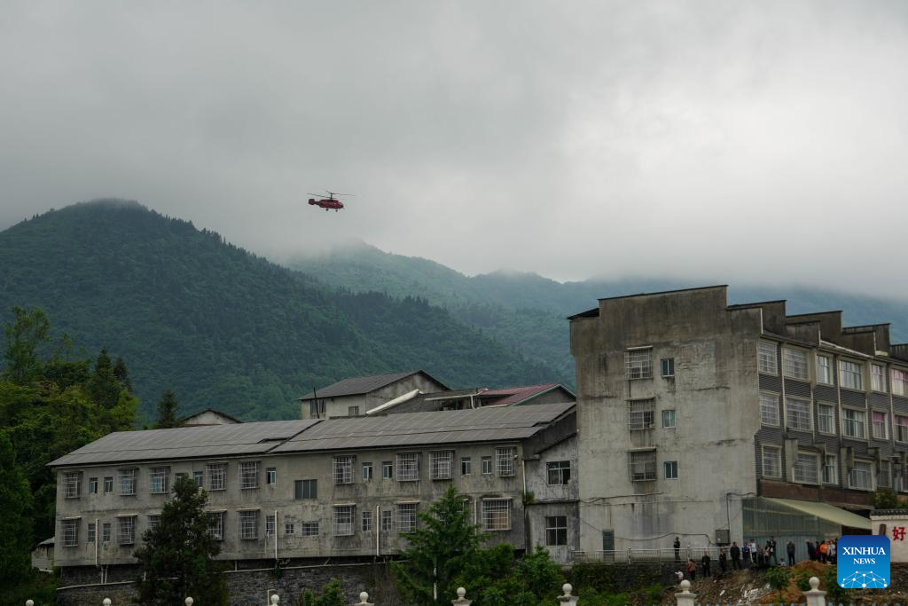 A helicopter, carrying disaster-affected villagers, flies towards a school in Nanbei Town, Shimen County, Changde City of central China's Hunan Province, May 21, 2026. Recently, some areas in Hunan have been hit by severe flooding, resulting in heavy casualties and property losses. Continuous heavy rainfall has lashed the province's Shimen County, leaving six people dead and 10 others missing so far, according to local authorities. A helicopter landed at a school in Nanbei Town of Shimen County on Thursday afternoon, completing the safe transfer of six villagers from Tianping Village of Hupingshan Town in Shimen. In preparation for a new round of rainfall, the emergency management department of Hunan has deployed helicopters to evacuate disaster-affected villagers in high-risk areas. (Xinhua/Xue Yuge)