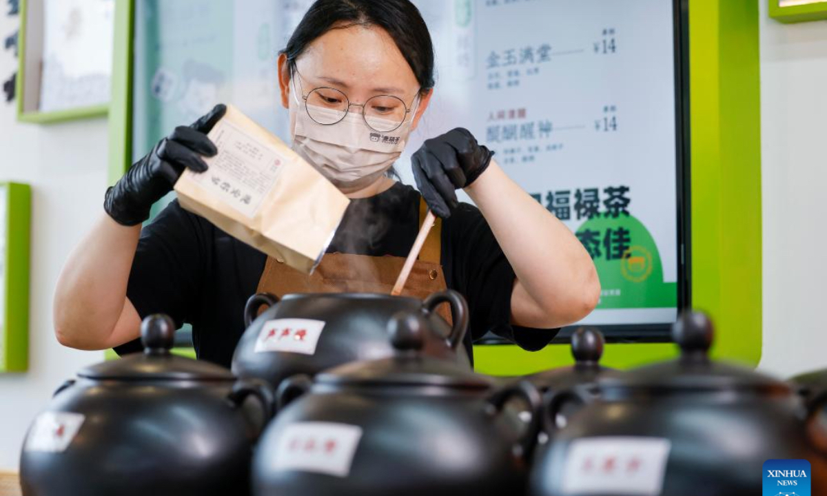 A staff pours formula materials into pots at a tea drink shop in Huangshan City, east China's Anhui Province, April 22, 2026. In Huangshan, the origin of famous tea varieties Huangshan Maofeng, Taiping Houkui and Qimen Black Tea, Chinese-style tea drink has become a new fashion in recent years. Wang Sun, who set up the Demingshe tea ceremony vocational school in Huangshan City, has led the research and promotion of Chinese-style tea drink since 2021. Appealing to young people's needs for healthy lifestyle, tea drink brands which combine tea and traditional Chinese medicines have become popular among youngsters. (Photo by Shi Yalei/Xinhua)