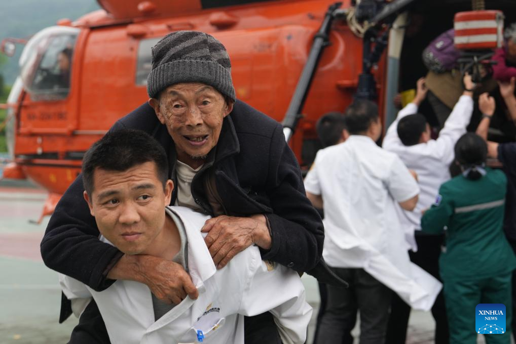 Medical workers help evacuate disaster-affected villagers at a school in Nanbei Town, Shimen County, Changde City of central China's Hunan Province, May 21, 2026. Recently, some areas in Hunan have been hit by severe flooding, resulting in heavy casualties and property losses. Continuous heavy rainfall has lashed the province's Shimen County, leaving six people dead and 10 others missing so far, according to local authorities. A helicopter landed at a school in Nanbei Town of Shimen County on Thursday afternoon, completing the safe transfer of six villagers from Tianping Village of Hupingshan Town in Shimen. In preparation for a new round of rainfall, the emergency management department of Hunan has deployed helicopters to evacuate disaster-affected villagers in high-risk areas. (Xinhua/Xue Yuge)