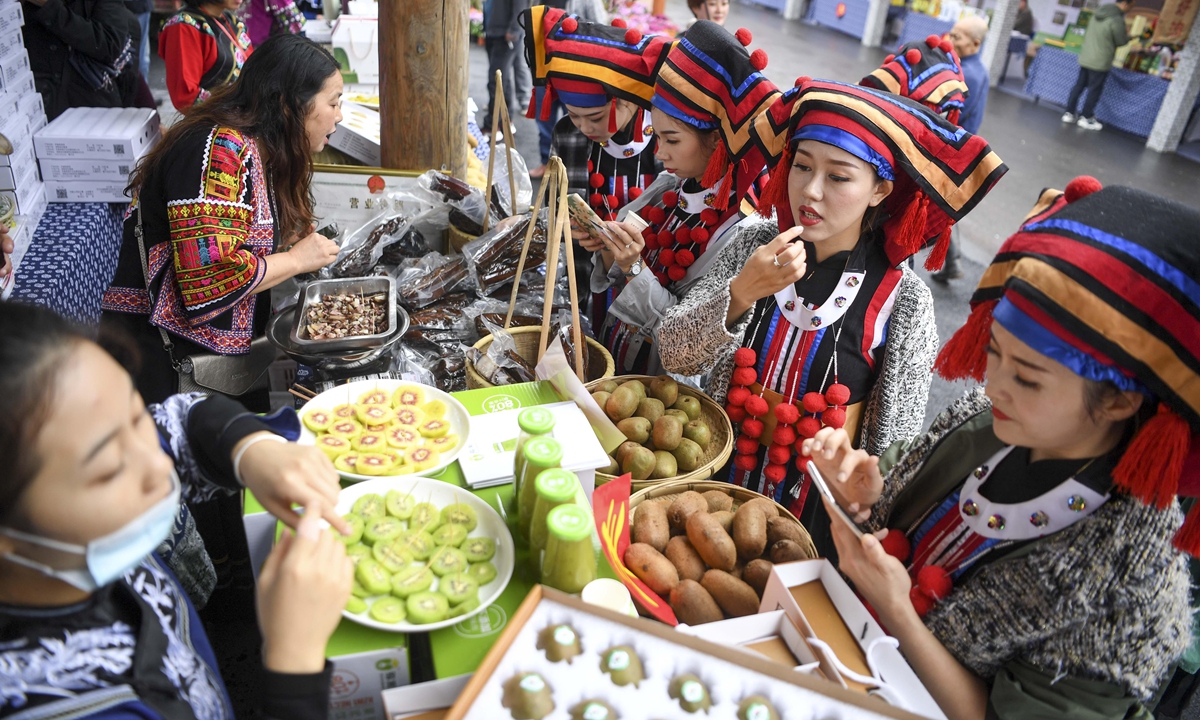 Women dressed in traditional Miao attire sample local specialties in Xiangxi, Central China's Hunan Province. Photo: VCG