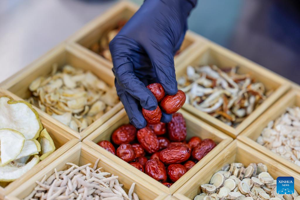 A staff grabs herbal materials at a tea drink shop in Huangshan City, east China's Anhui Province, April 22, 2026. In Huangshan, the origin of famous tea varieties Huangshan Maofeng, Taiping Houkui and Qimen Black Tea, Chinese-style tea drink has become a new fashion in recent years. Wang Sun, who set up the Demingshe tea ceremony vocational school in Huangshan City, has led the research and promotion of Chinese-style tea drink since 2021. Appealing to young people's needs for healthy lifestyle, tea drink brands which combine tea and traditional Chinese medicines have become popular among youngsters. (Photo by Shi Yalei/Xinhua)