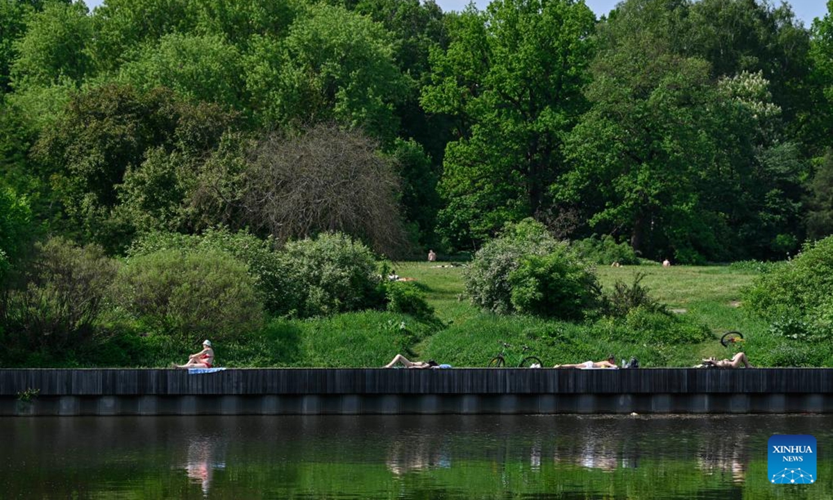 People sunbathe near a pond at VDNH (The Exhibition of Achievements of National Economy) in Moscow, Russia, on May 21, 2026. Moscow has been experiencing a heatwave these days. The temperature hit 30 degrees Celsius at noon on May 20, breaking a 129-year record in May. (Photo by Alexander Zemlianichenko Jr/Xinhua)