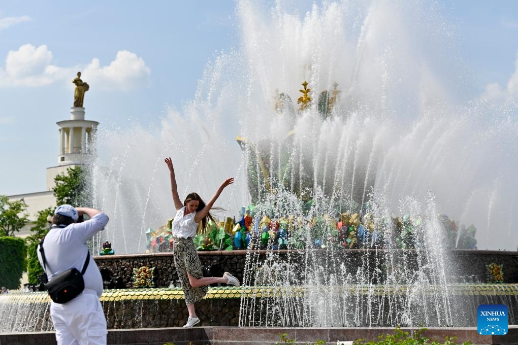 A woman poses for photo near a fountain at VDNH (The Exhibition of Achievements of National Economy) in Moscow, Russia, on May 21, 2026. Moscow has been experiencing a heatwave these days. The temperature hit 30 degrees Celsius at noon on May 20, breaking a 129-year record in May. (Photo by Alexander Zemlianichenko Jr/Xinhua)