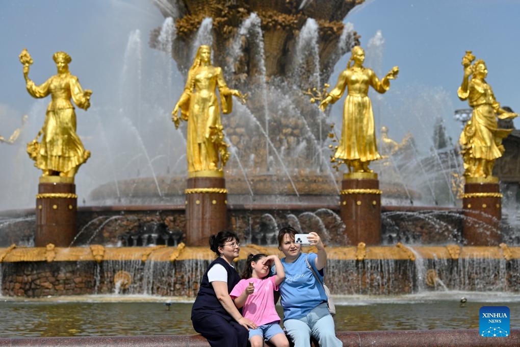 People take a selfie in front of the Friendship of Peoples fountain at VDNH (The Exhibition of Achievements of National Economy) in Moscow, Russia, on May 21, 2026. Moscow has been experiencing a heatwave these days. The temperature hit 30 degrees Celsius at noon on May 20, breaking a 129-year record in May. (Photo by Alexander Zemlianichenko Jr/Xinhua)