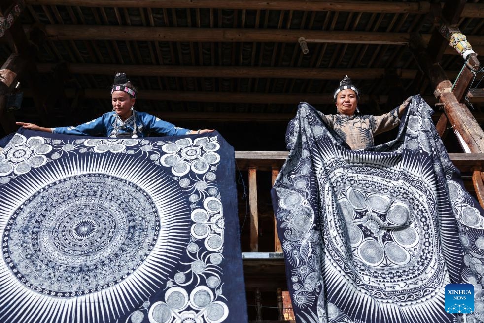 Inheritor Zhang Shixiu (R) and a villager dry wax dyeing artworks in Paimo Village, Danzhai County of southwest China's Guizhou Province, May 20, 2026. Miao wax dyeing, a craft inherited through generations among the Miao ethnic group in southwest China's Guizhou, was listed as a national intangible cultural heritage in 2006. The folk artwork is famous for its elegant color, graceful patterns and rich cultural expressions. (Photo: Xinhua)